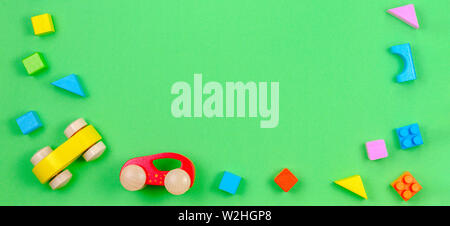 Baby Kind Spielsachen banner Hintergrund. Wooden Cubes und zwei Autos auf grünem Hintergrund Stockfoto