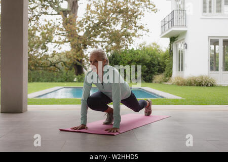 Active Senior frau yoga auf der Trainingsmatte in der Halle zu Hause. Stockfoto