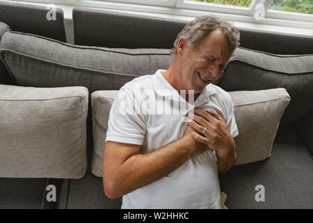 Aktive ältere Menschen leiden unter Schmerzen in der Brust auf dem Sofa in ein gemütliches Heim Stockfoto