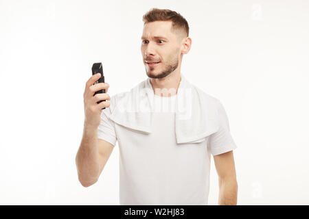 Junger Mann auf dem weißen Hintergrund rasiert sein Gesicht Haare in die Kamera. Stockfoto