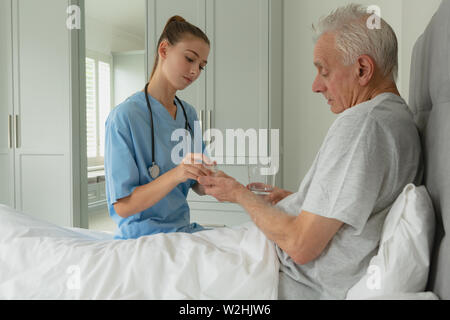 Weibliche Arzt, der Medizin zu Active Senior Patienten im Schlafzimmer Stockfoto