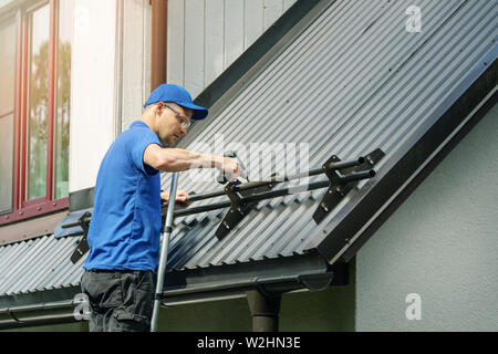 Dachdecker Installation von Snow Guard auf Metall Dach Stockfoto