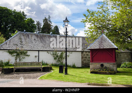 Alten Brunnen und Sitzbank auf der Grünen in der Erhaltung Dorf in Cawdor Immobilien. Cawdor, Nairn, Nairnshire, Highland, Schottland, Großbritannien, Großbritannien Stockfoto