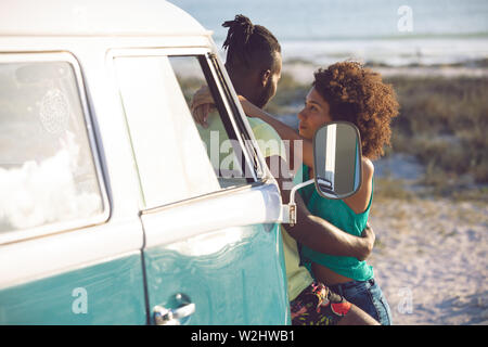 Paare, die in der Nähe von Camper am Strand Stockfoto