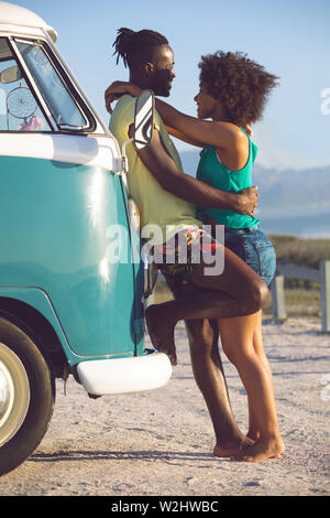 Paare, die in der Nähe von Camper am Strand Stockfoto