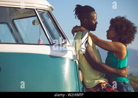 Paare, die in der Nähe von Camper am Strand Stockfoto