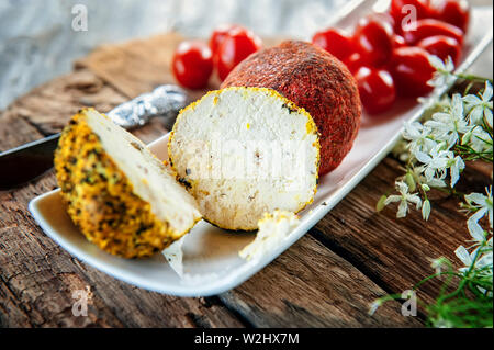 Delikatesse runden Käse Belper Knoll mit Gemüse und Kräutern auf einem Holztisch. Frische Produkte vom Bauernhof in Russland Stockfoto