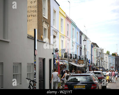 Pastellfarbenen Häusern, Autos und Menschen in der Portobello Road, London, UK geparkt. Stockfoto