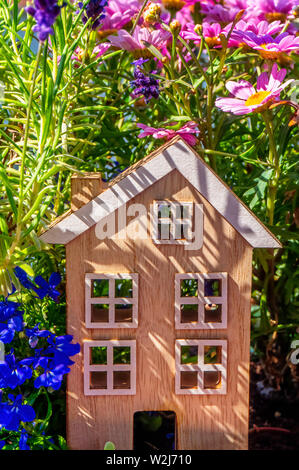 Holzhaus steht zwischen Blumen in der Landschaft Stockfoto