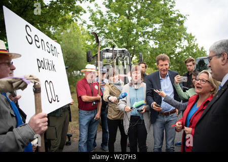 Spremberg, Deutschland. 09 Juli, 2019. Svenja Schulze (2. von links), Minister für Umwelt, Naturschutz und Reaktorsicherheit, und Brandenburgs Wirtschaftsminister Jörg Steinbach (r, beide SPD) von Demonstranten vor der Braunkohle empfangen werden - Gefeuert von Kraftwerk Schwarze Pumpe chwarze' mit einem Plakat DES ensenpolitik CO2". Credit: Soeren Stache/dpa/Alamy leben Nachrichten Stockfoto