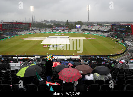 Fans sitzen unter Sonnenschirmen im steht als Regen stoppt während der ICC World Cup, Halbfinale im Emirates Old Trafford, Manchester spielen. Stockfoto