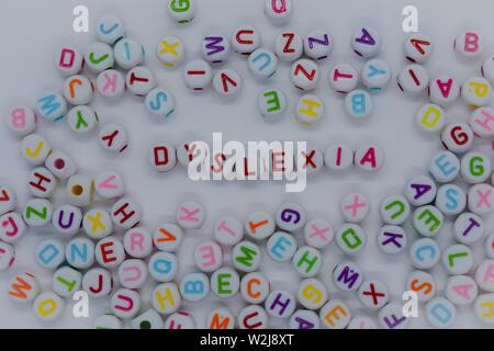 Legasthenie, in roten Buchstaben, die durch ein Meer von zufälligen Buchstaben umgeben, auf einem weißen Hintergrund. Kreatives Konzept: Lesen Behinderung Stockfoto