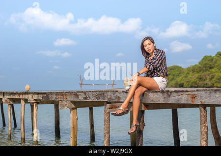 Frauen auf dem hölzernen Brückenpfeiler Boot im Meer und dem hellen Himmel auf Koh Kood, trat in Thailand. Stockfoto