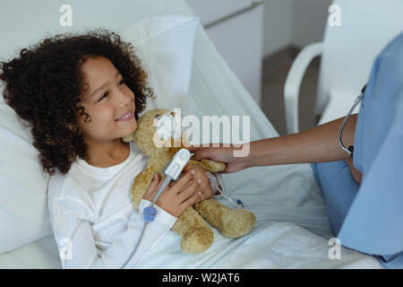 Weibliche Arzt, Teddybären zu Kind Patienten auf der Station Stockfoto