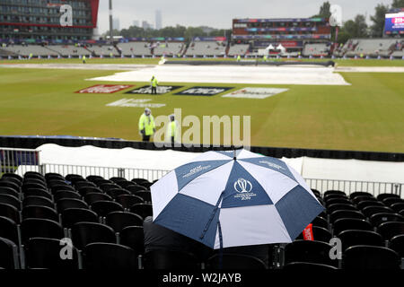 Fans sitzen unter Sonnenschirmen im steht als Regen stoppt während der ICC World Cup, Halbfinale im Emirates Old Trafford, Manchester spielen. Stockfoto