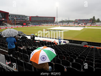 Fans sitzen unter Sonnenschirmen im steht als Regen stoppt während der ICC World Cup, Halbfinale im Emirates Old Trafford, Manchester spielen. Stockfoto