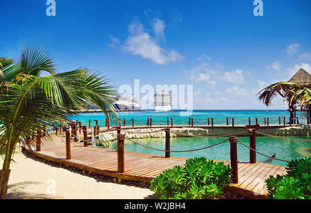 Blick vom Strand im Tropical Resort auf Kreuzfahrtschiffen angedockt am Port Stockfoto