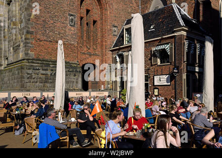Groningen, Niederlande - 27. Februar 2019: die Menschen genießen Sie einen sonnigen Tag auf der Terrasse des Cafe Restaurant De kostery an Martini Kirche (Marti Stockfoto