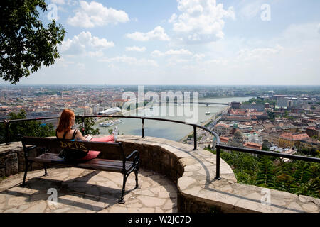 Eine Frau sitzt auf einer Bank allein nbjoying der Blick über Budapest von Gellert Hill Stockfoto