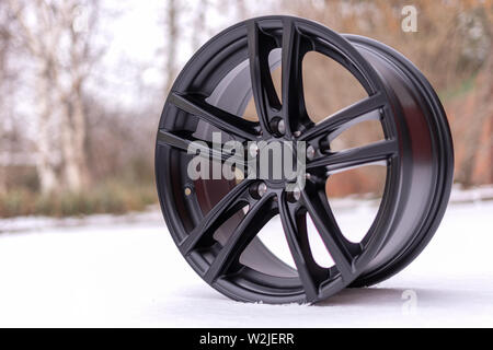 Neues, elegantes schwarzes Gehäuse aus gebürstetem Aluminium Leichtmetallfelgen, auf weißem Schnee. Winter. Bis zu schließen. Stockfoto