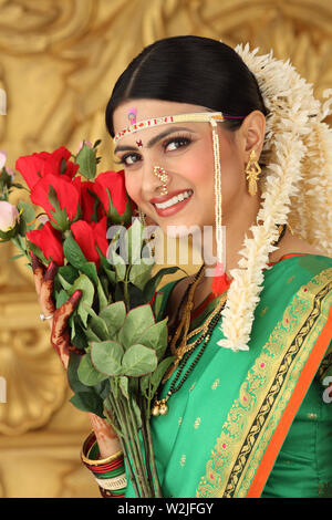 Indische Braut mit Blumenstrauß und lächelnd Stockfoto