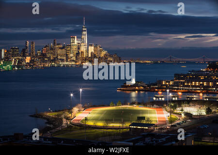 New York City Financial District Wolkenkratzer in der Nacht mit dem Hudson River und Weekhawken, New Jersey Riverfront. World Trade Center, Manhattan, NY Stockfoto