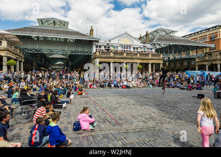 Eine Street Performer unterhält Massen von Touristen am Covent Garden Market, London Stockfoto