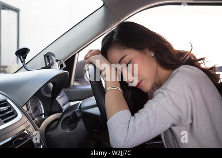 Müde junge Frau schlafen im Auto, harte Arbeit führt zu einer schlechten Gesundheit, Sitzen, Schlafen, während das Auto auf einem roten Licht ist, Stau oder überarbeiteten Konzept Stockfoto