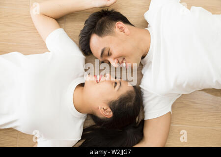 Asiatische Paar an jedem anderen suchen und auf dem Boden liegend zu Hause, die wahre Liebe und Hochzeit Fotografie Konzept Stockfoto