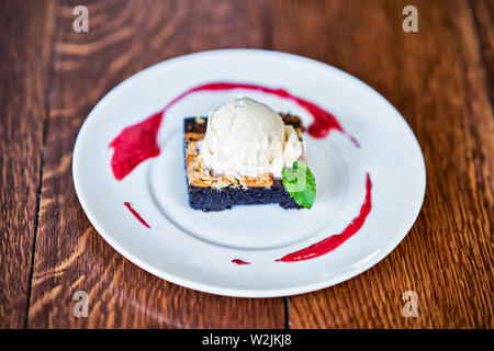 Brownie Sundae mit einer Kugel Vanilleeis und Berry Sauce Stockfoto