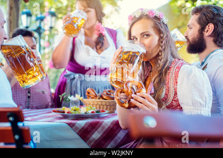 Frau in Tracht, in die Kamera beim Trinken einer Masse von Bier Stockfoto