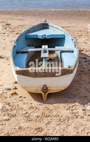 Eine blau-weiße Ruderboot oder Skiff an einem Strand in Richtung des Wassers zeigen Stockfoto