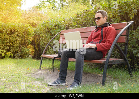Junger Mann auf seinem Laptop mit wireless Internet im ländlichen Raum verbinden. Internet Verbindung ermöglicht Menschen, überall zu arbeiten. Freelancer Programmierer Stockfoto
