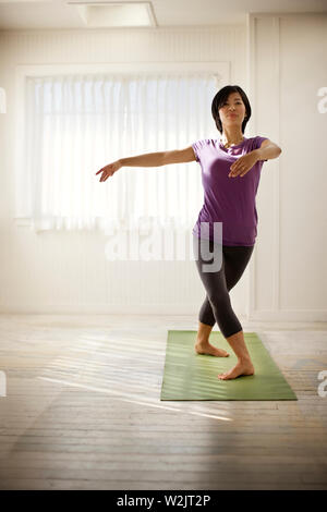 Porträt einer jungen Frau mit Yoga auf einer Matte innerhalb Ihres Hauses. Stockfoto
