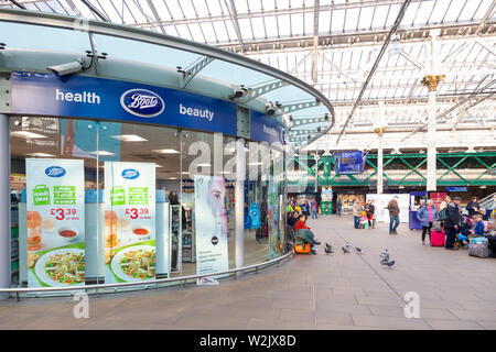 Äußere des Stiefel Shop und Passagiere warten auf Züge im Bahnhof Waverley Station, Edinburgh, Schottland, Großbritannien Stockfoto