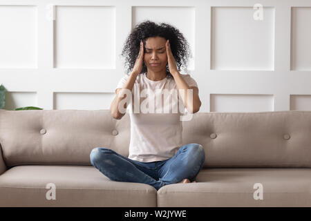 Verärgert betonte Junge afrikanische Frau massage Tempel fühlen starke Kopfschmerzen. Stockfoto