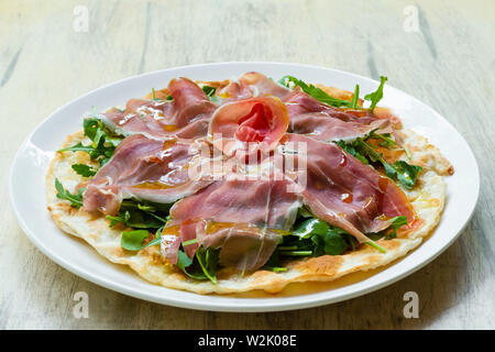 Focaccia di Recco traditionelle italienische Gericht aus der Region Ligurien, Genua, gefüllt mit stracchino Käse, Parmaschinken DOP, Rucola und Olivenöl Stockfoto