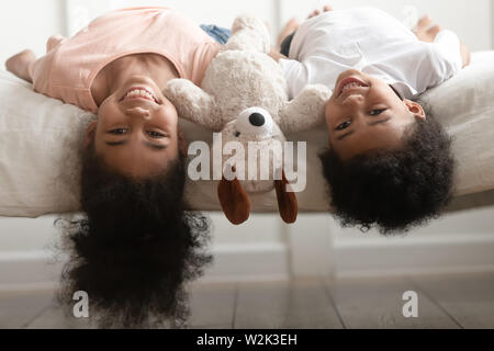 Lustige kleine Jungen und Mädchen liegt mit der Oberseite nach unten auf das Bett Stockfoto