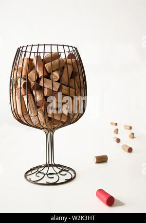 Korken aus der Flasche in eine Vase simuliert ein Glas Wein und ein paar Korken neben der Vase mit einem weißen Hintergrund. Stockfoto