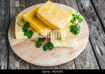 Große Auswahl an Käse auf einem alten, rustikalen Holztisch. Stockfoto