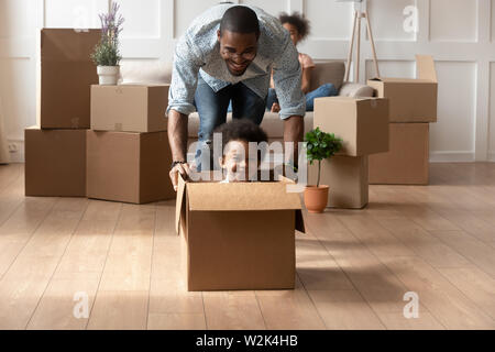 Happy afrikanischen Vater spielen mit kleinen Sohn Reiten in Feld Stockfoto