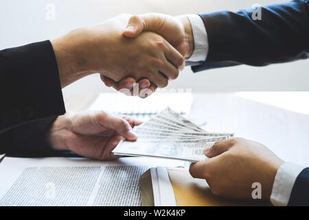 Unehrlich in der Geschäftswelt zu betrügen illegal Geld, Geschäftsmann handshake Geld von Dollarnoten in den Händen von während der Erfolg der Deal, Bestechung und corru Stockfoto