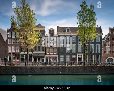 Fahrräder und Gebäude entlang einer Gracht in Amsterdam, Niederlande Stockfoto