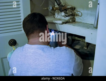 Eine fokussierte löten Flamme aus einer Heizung und Klimaanlage (HVAC) Techniker Reparatur eines undichten Warmwasserbereiter. Stockfoto