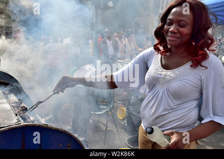 Frau grillen Huhn Stücke auf Öl Grill an der Bristol St Pauls Karneval drum Stockfoto