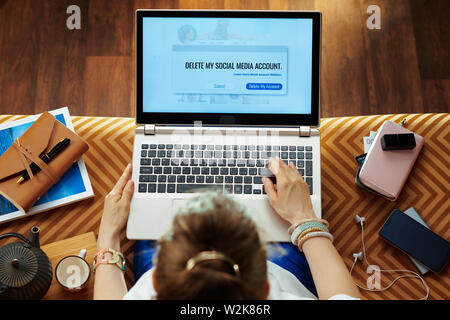 Obere Ansicht von trendigen Frau sitzt auf der Couch im Wohnzimmer blockieren Social Media Account. Stockfoto