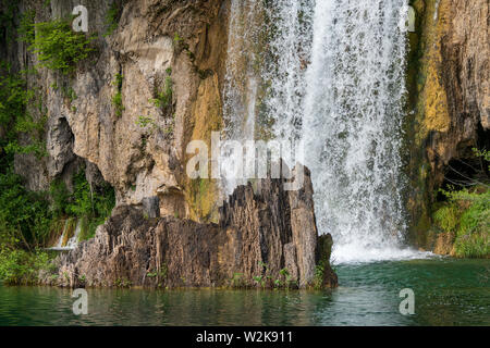 Kristallklares, reines Wasser, ausgegossen bemoosten Felsen in einem wunderschönen azurblauen See im Nationalpark Plitvicer Seen in Kroatien Stockfoto