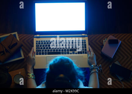 Obere Ansicht der elegante Frau sitzt auf einem Sofa in der modernen Wohnzimmer suchen Blue Light Computer Bildschirm auf einem Laptop. Stockfoto