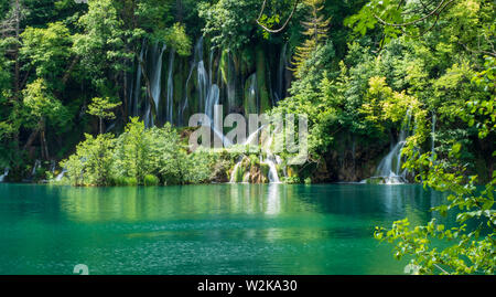 Kristallklares, reines Wasser, ausgegossen bemoosten Felsen in einem wunderschönen azurblauen See im Nationalpark Plitvicer Seen Plitvicer Seen, Kroatien Stockfoto