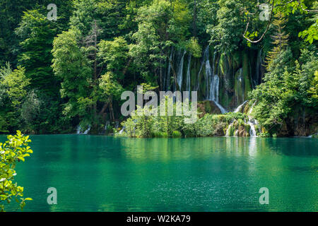 Kristallklares, reines Wasser, ausgegossen bemoosten Felsen in einem wunderschönen azurblauen See im Nationalpark Plitvicer Seen Plitvicer Seen, Kroatien Stockfoto